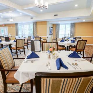 An elegantly set dining room with tables and chairs, featuring blue napkins and tasteful decor.