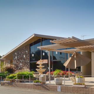 A modern building with outdoor seating and landscaping on a sunny day.