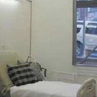 A hospital room with a single bed and a window.