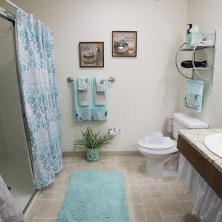 A well-decorated bathroom with a shower curtain, towels, and a bath mat in matching pastel colors.