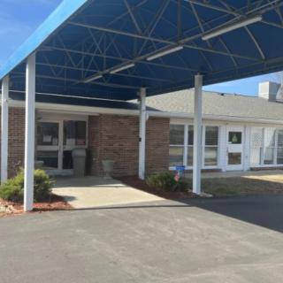 A building entrance with a blue canopy and paved walkway.