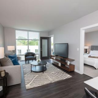 A modern living room with a view into the adjacent bedroom, featuring stylish furniture and decor.