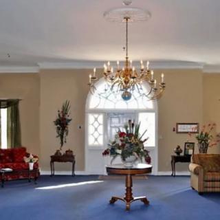 An elegant living room with a chandelier, blue carpet, and classic furniture.
