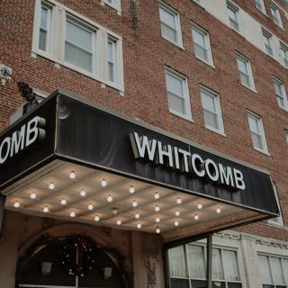 The exterior of the Whitcomb hotel with its illuminated marquee sign.