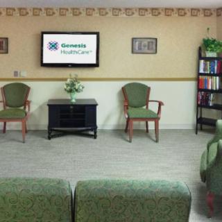 A waiting room with chairs, a television, and a bookshelf.