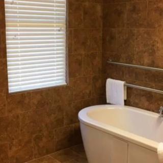 A cozy bathroom with a standalone bathtub and tiled walls.