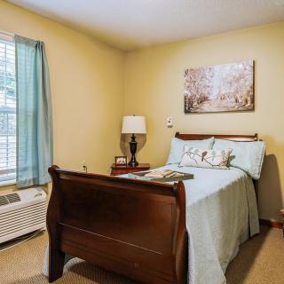 Cozy bedroom with a wooden bed, lamp, and decorative painting.