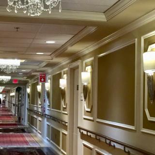 A luxurious hotel hallway featuring elegant lighting and patterned carpet.