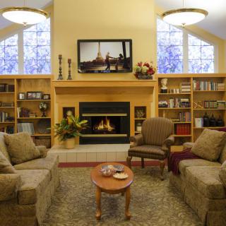 A cozy living room featuring a fireplace, sofas, and built-in bookshelves.