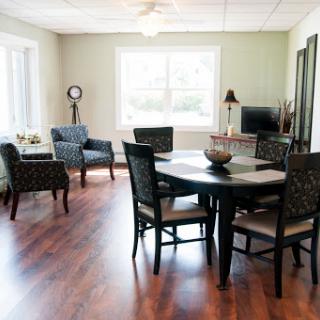 A cozy and well-lit dining area featuring a round table and comfortable seating, perfect for gatherings.