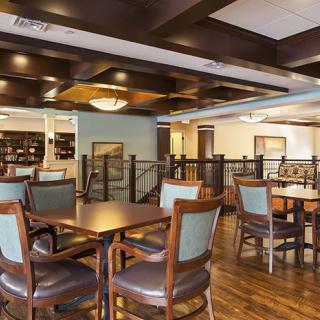A spacious and elegantly designed dining area featuring wooden floors, tables, and chairs.