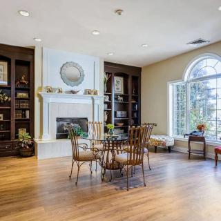 A cozy living room with a fireplace, surrounded by built-in bookshelves and a large window.