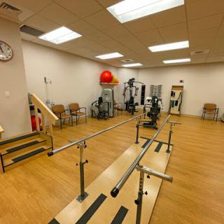 A physical therapy room equipped with exercise apparatus including parallel bars and fitness machines.