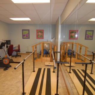 A rehabilitation room equipped with parallel bars and wooden ramps for physical therapy exercises.