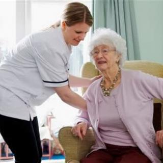 A caregiver assisting an elderly woman in a comfortable setting.