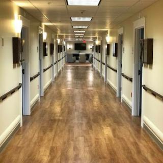 A well-lit corridor with doors on either side, featuring wooden flooring and a clean, organized appearance.