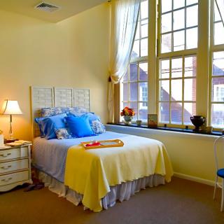 A cozy bedroom with a single bed and large windows allowing natural light to fill the room.