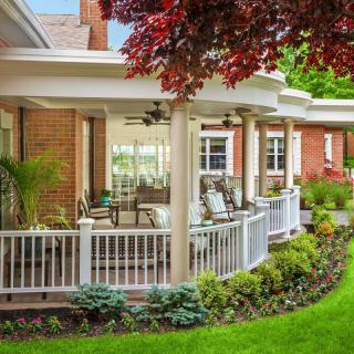 A charming house with a spacious porch overlooking a well-maintained garden.