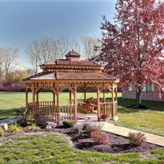 A beautiful wooden gazebo surrounded by lush greenery and blooming trees, perfect for enjoying the outdoors.