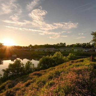 A picturesque sunset over a tranquil lake surrounded by lush greenery.