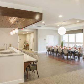 A modern dining room with a large table set for a meal and an adjacent kitchen area.