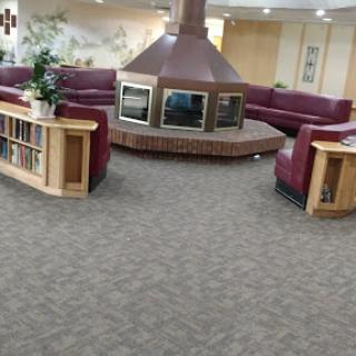 A cozy seating area featuring a central fireplace and bookshelves in a welcoming lobby.