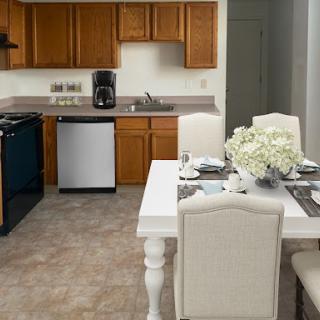 A bright and modern kitchen with a cozy dining area, featuring wooden cabinets and a white dining table.