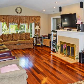 A cozy living room with hardwood floors, a fireplace, and a large TV.