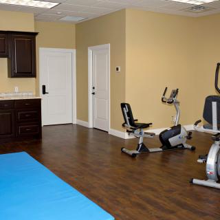 A compact home gym featuring a stationary bike and exercise mat in a small room.