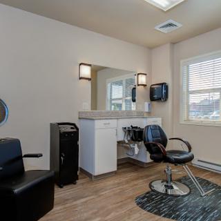 A modern salon interior featuring a barber chair, workstation, and well-lit mirror area.
