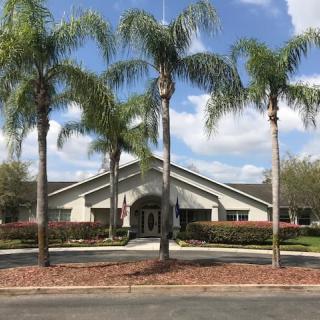 A building surrounded by palm trees under a blue sky with clouds.