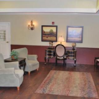A cozy lobby area with chairs, a table, and decorative paintings.