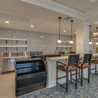A modern kitchen area with a sleek countertop, bar stools, and stylish pendant lighting.
