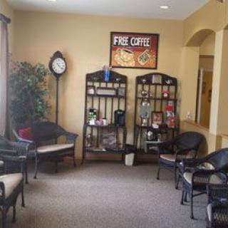 A cozy waiting room with chairs, decorative shelves, a clock, and an indoor plant.
