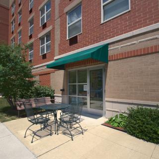 Entrance to an apartment building with outdoor seating and a green awning.