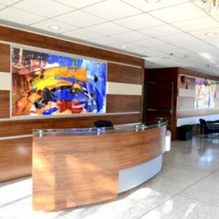 A modern reception area with a wooden desk and colorful artwork on the wall.