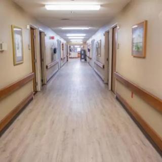 A well-lit hallway with wooden flooring and artwork on the walls.
