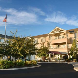 A multi-story residential building with a driveway and flagpole in front.