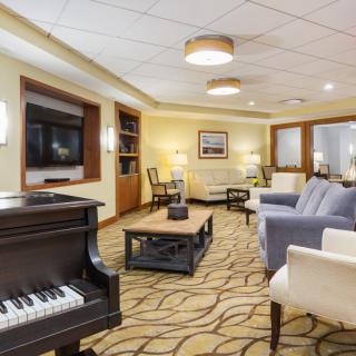 A cozy lounge area featuring a piano, comfortable seating, and a television.