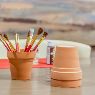 Art supplies including paintbrushes and clay pots set up for a crafting session.