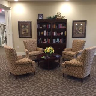 A cozy seating area with four armchairs arranged around a coffee table, complemented by a bookshelf in the background.