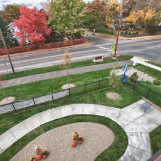 Aerial view of a small park with autumn trees and a playground, adjacent to a road.