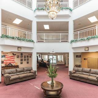 Spacious lobby area featuring sofas and a central chandelier.