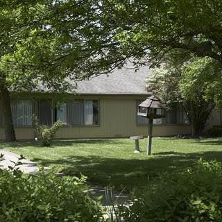 A suburban house surrounded by trees and a well-maintained yard.