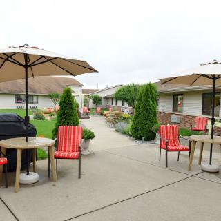A well-maintained patio area with tables, chairs, and umbrellas set amidst beautiful landscaping.