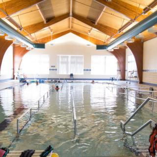 An indoor swimming pool with a wooden ceiling and several lanes for swimming practice.