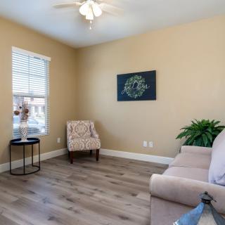A minimalist living room with a beige sofa, an accent chair, and wall art.