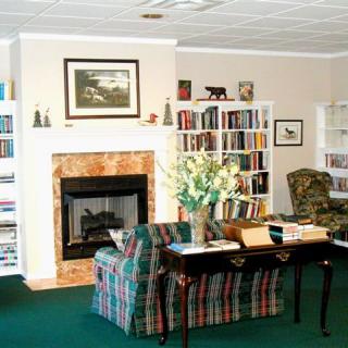 A cozy living room featuring a fireplace, bookshelves filled with books, and comfortable seating arrangements.