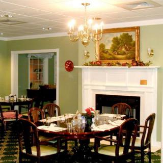 An elegant dining room with a fully set table, chandelier, and fireplace.