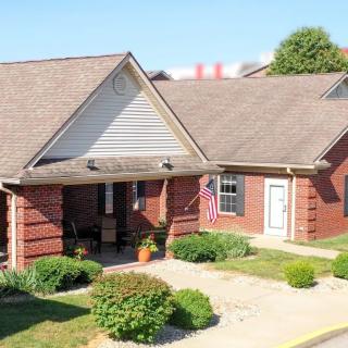 A suburban brick house with a garden and an American flag displayed outside.